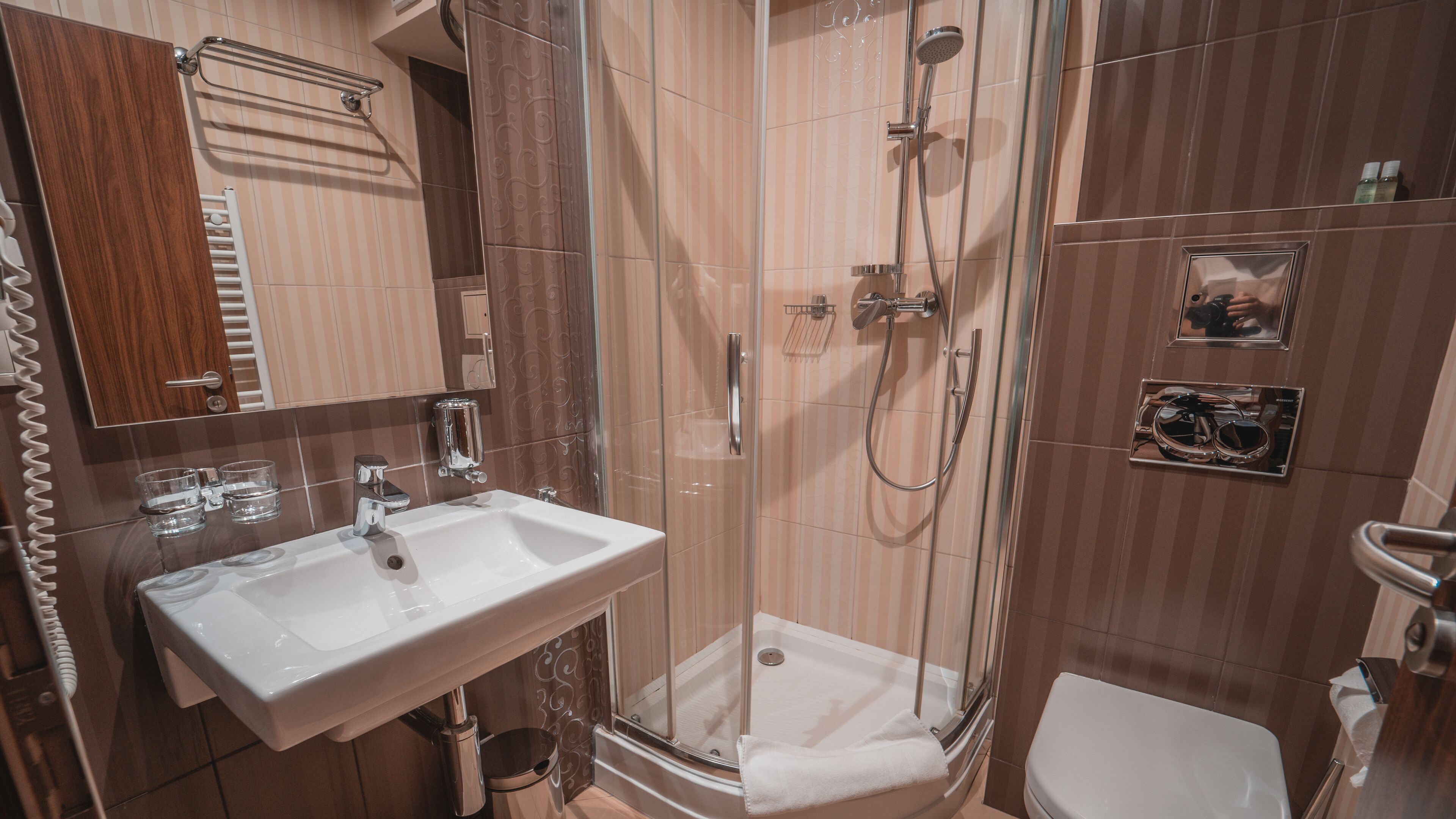 Un baño con un lavamanos blanco, cabina de ducha de vidrio y un inodoro.
