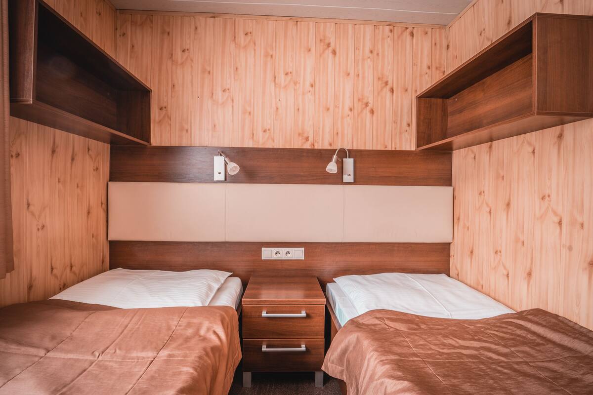 Una cabaña con dos camas, paredes de madera y estanterías empotradas.