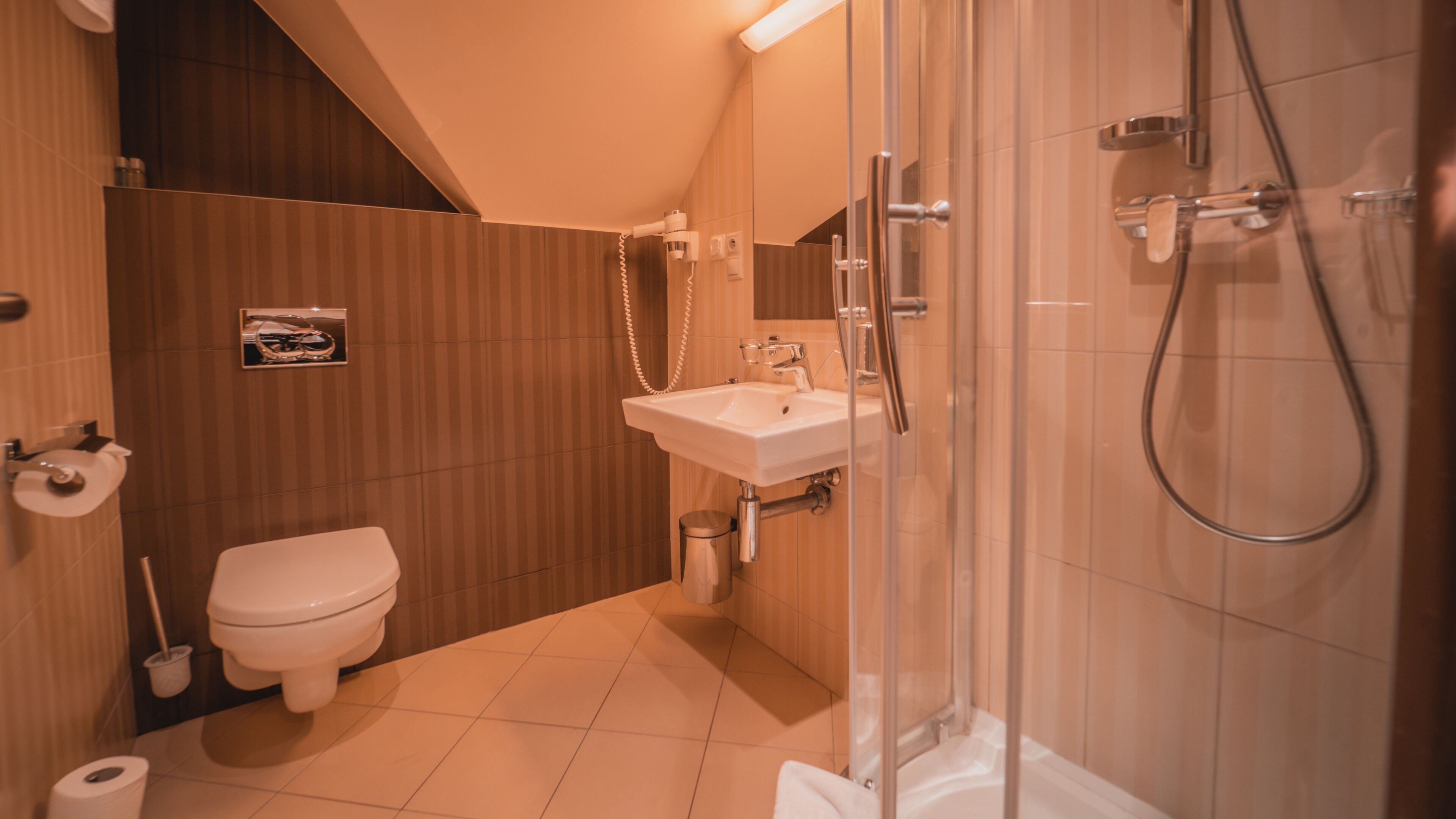 Een moderne badkamer met toilet, wastafel en douche.