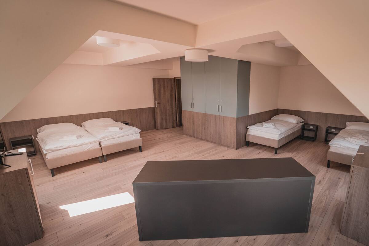 Un dormitorio tipo loft moderno con dos camas, una mesa grande en el centro y un armario.
