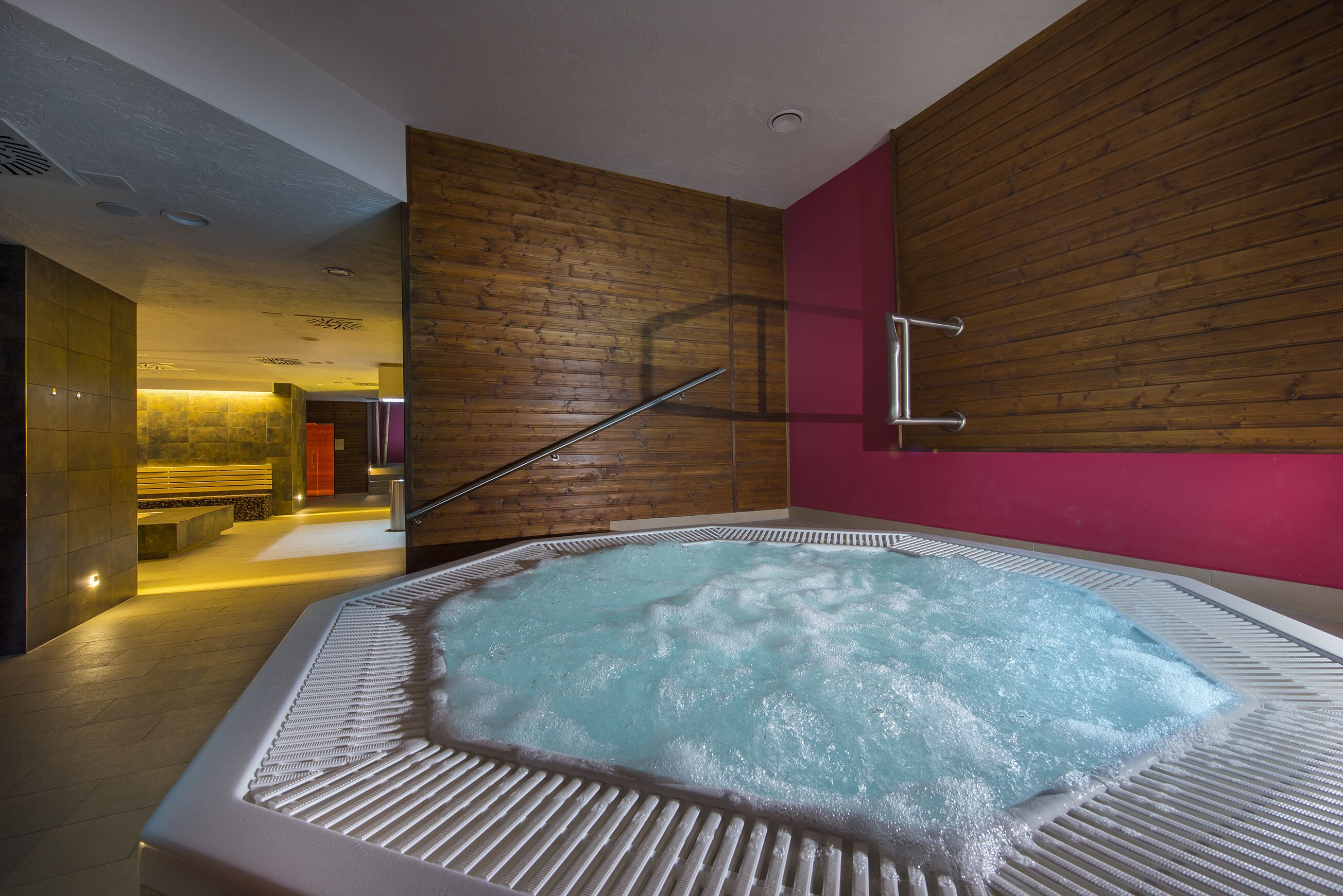 A modern spa area with a hot tub, wooden walls, and a staircase.