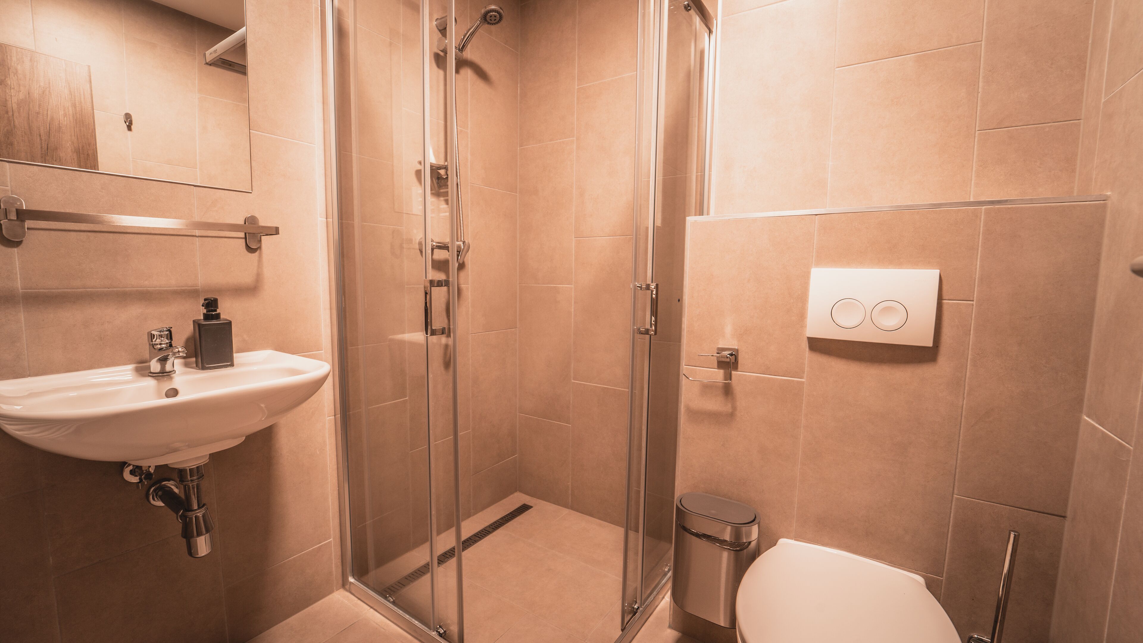A modern bathroom with a glass-enclosed shower, a sink, and a toilet.