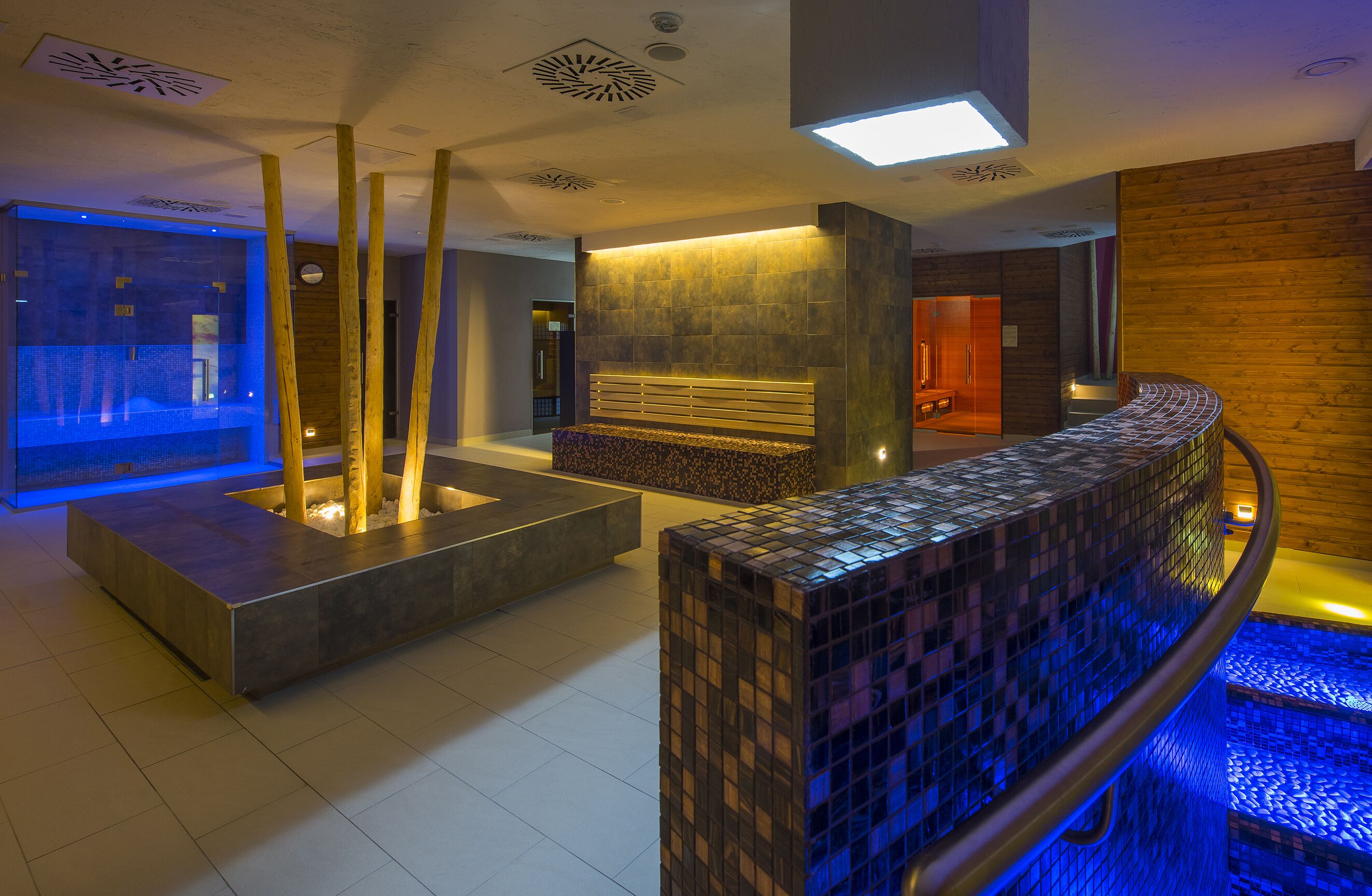 Uma área de spa moderna com banheira de pedra aquecida, balcão de recepção e compartimento de vidro.