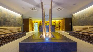 Un vestíbulo moderno con una fuente central, paredes de azulejos y un mostrador de recepción.