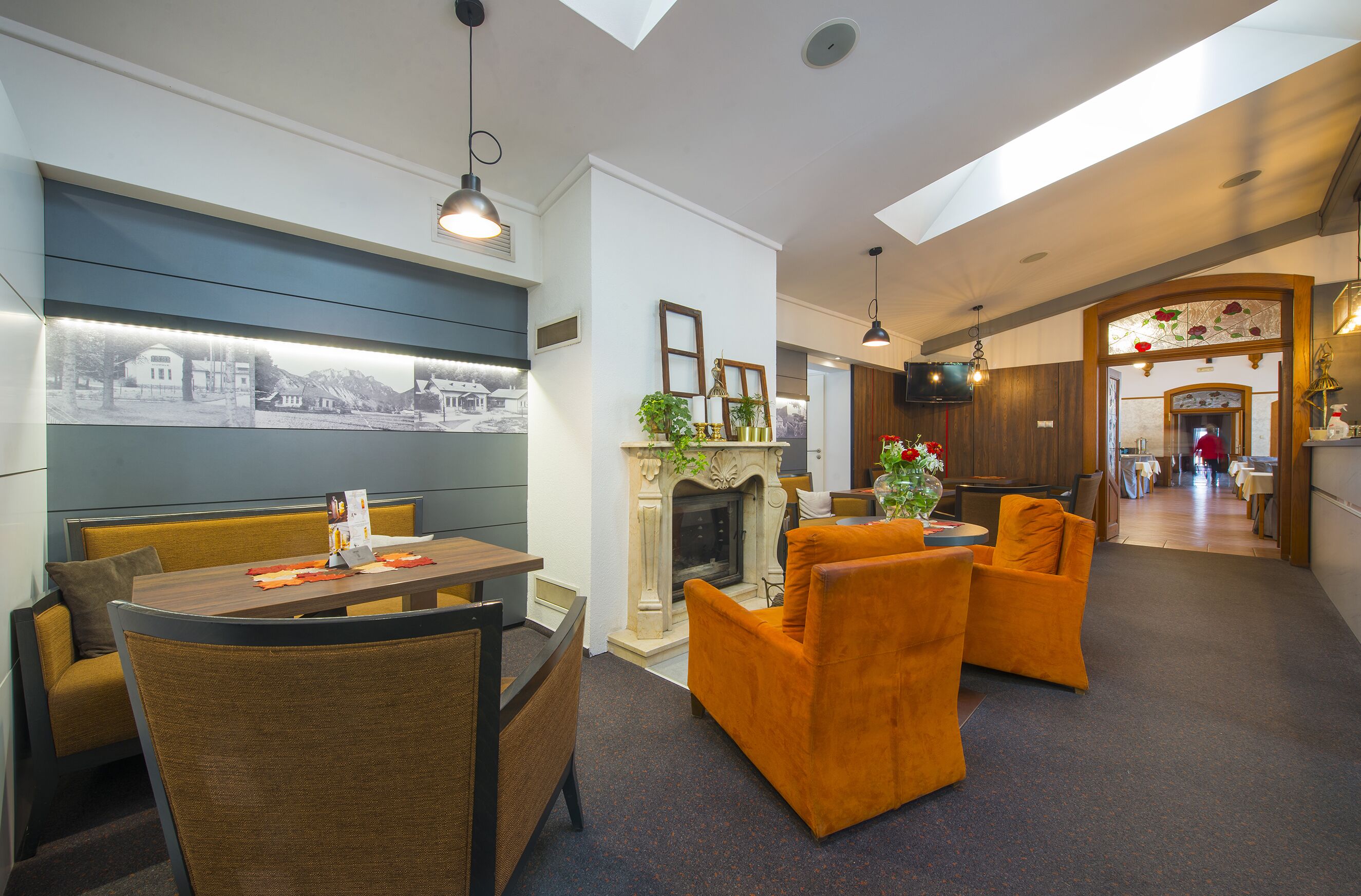A hotel lobby with a dining area, seating, a fireplace, and a view of the outside.