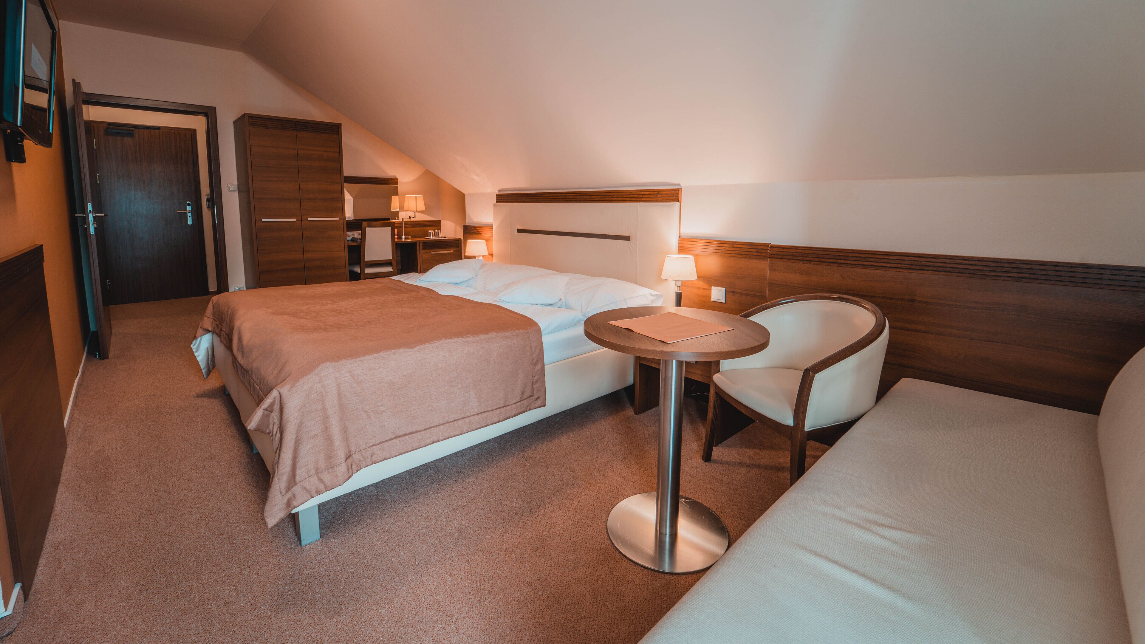 A hotel room with two beds, a round table, and a chair.