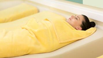 Une personne allongée sur un fauteuil de spa, recouverte d’une serviette jaune.