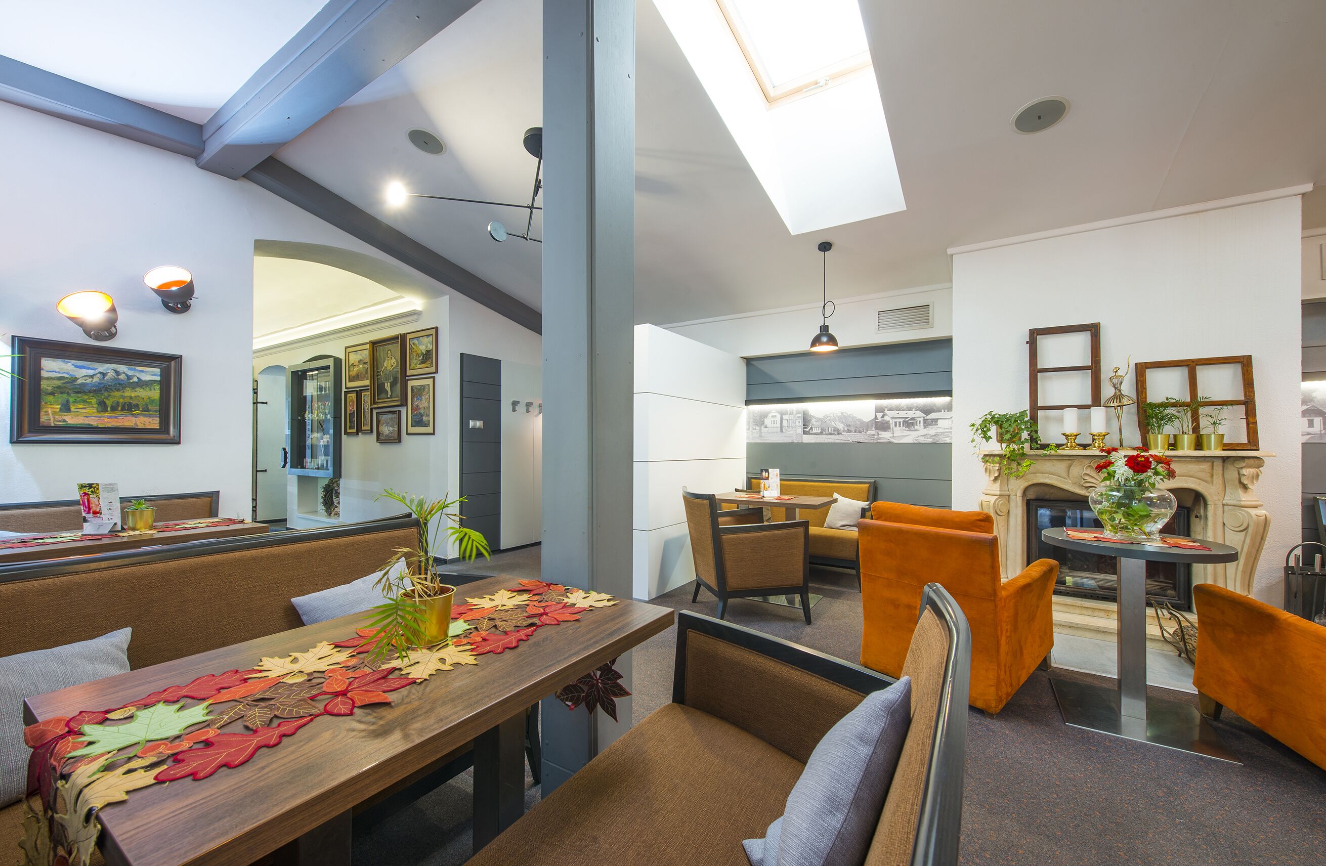 A modern dining area with a wooden table, orange chairs, and a fireplace.