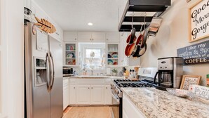 A modern kitchen with white cabinets, stainless steel appliances, and a granite countertop. - Copacabana - Waves of Fun! (Lubbock)