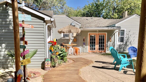A wooden deck leading to a house with a thatched roof and a porch. - Copacabana - Waves of Fun! (Lubbock)