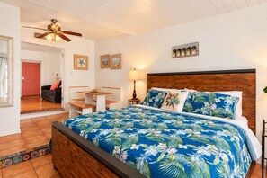 Une chambre à coucher comprenant un lit, un bureau, une chaise, un ventilateur de plafond et une porte.