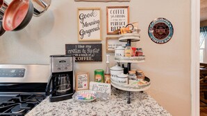 A kitchen counter with a coffee maker, a coffee station, and various coffee-related items. - Copacabana - Waves of Fun! (Lubbock)