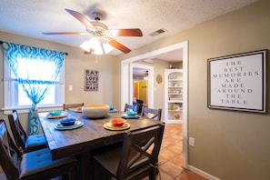 A dining area with a wooden table, blue and orange plates, and a ceiling fan. - Copacabana - Waves of Fun! (Lubbock)