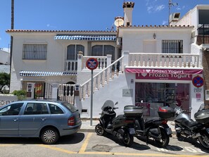 Edifício com fachada onde se lê 'Frozen Yogurt' e placa indicando vaga de estacionamento com 6 metros.