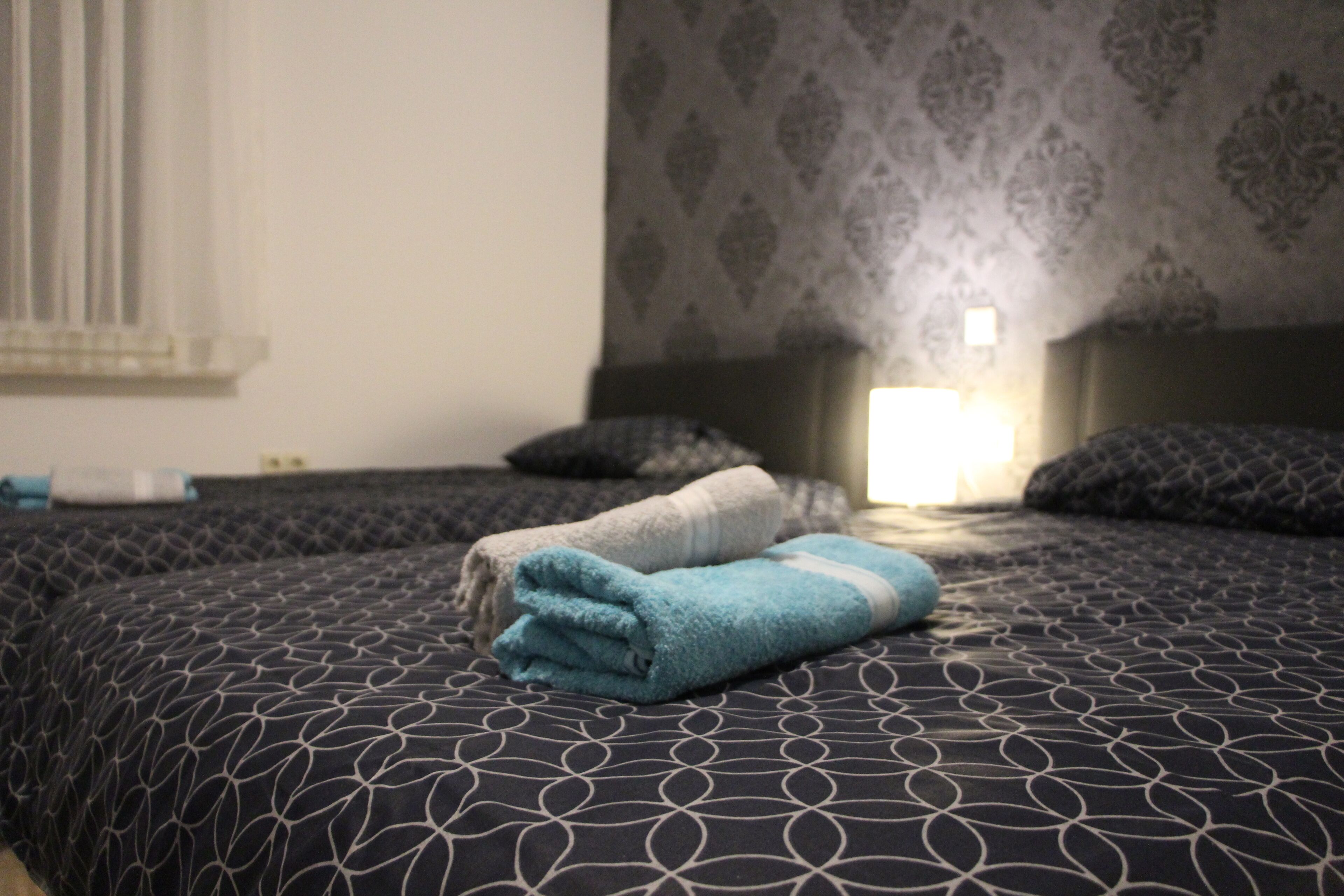 Een hotelkamer met een groot bed, een nachtkastje en behang met een patroon.