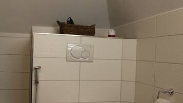 Un baño pequeño con inodoro, ducha y un perchero para toallas.