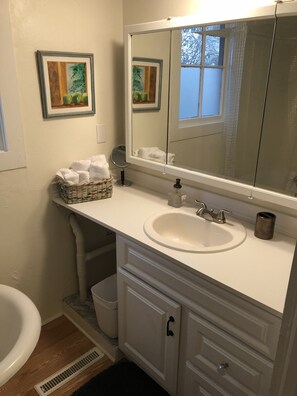 Bathroom features a sink, mirror, and toilet, with a wicker basket holding towels.