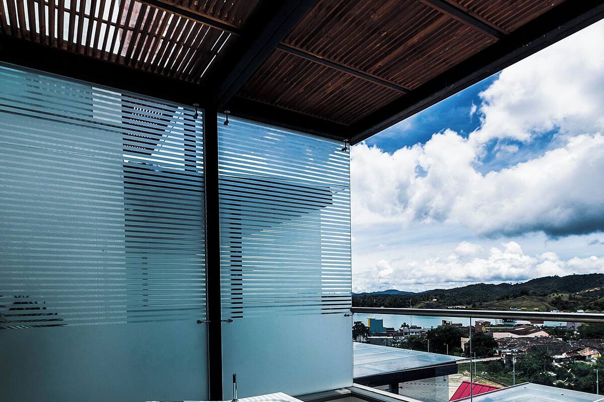 A modern bathroom with a large bathtub, a view of the city, and a wooden ceiling.