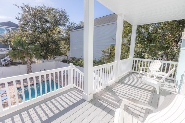 A covered porch with white railings and a pool. - FADE AWAY -New 5 Bedroom House Only Steps From The Ocean With a Private Pool (Surfside Beach)