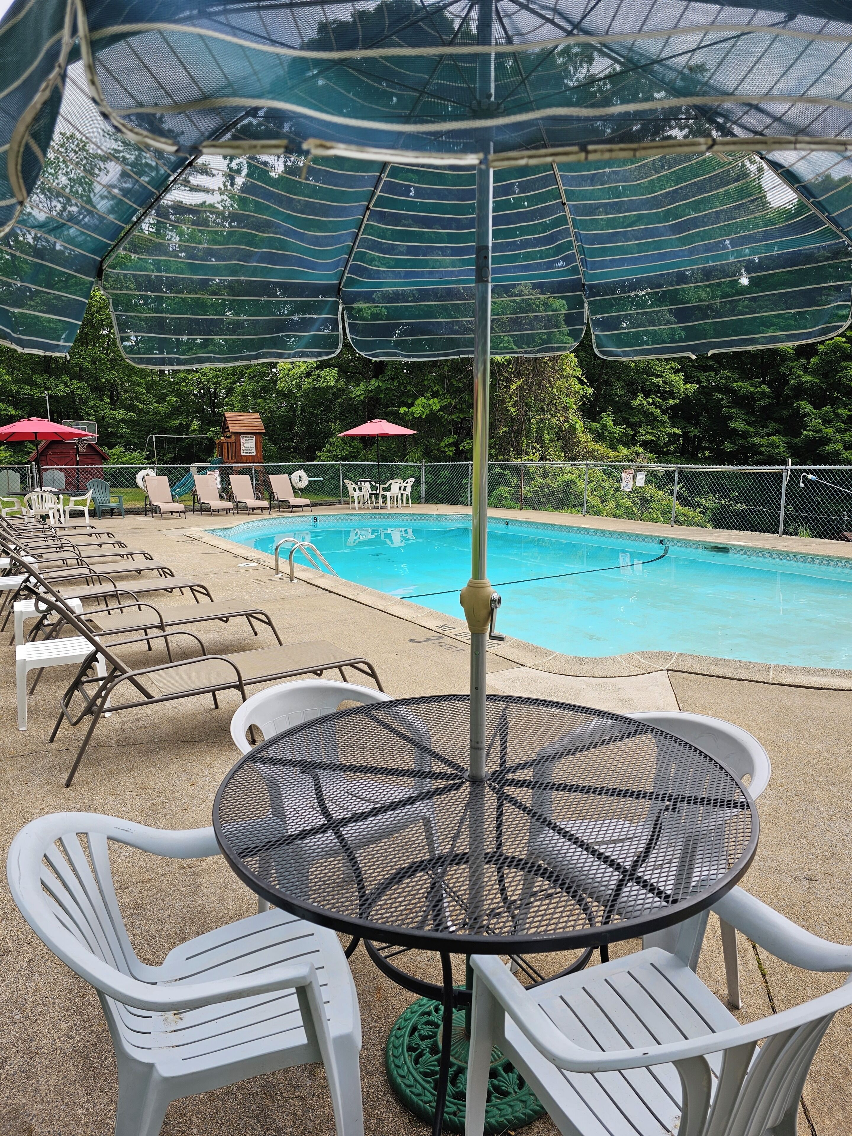 Un espace piscine aménagé avec des chaises longues, des parasols et une table.