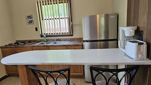 Cucina con frigorifero in acciaio inox, macchina del caffè e tostapane.