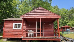 Une cabane rouge avec un porche, une fenêtre et un drapeau américain.