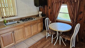 Une cuisine compacte avec des meubles en bois, une cuisinière à gaz, un évier et une petite table à manger avec deux chaises.