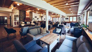 Un hall d’entrée spacieux avec un plafond en bois, des sièges confortables, une cheminée et un espace d’accueil.
