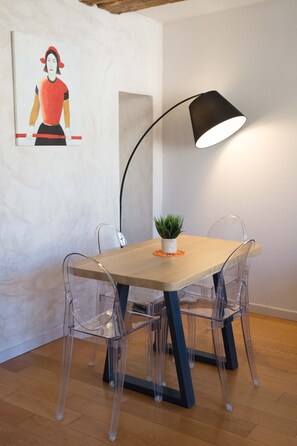 A dining area with a wooden table, four clear chairs, a black lamp, and a small potted plant. - Superb apartment in the city center (Tournus)