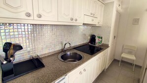A kitchen with white cabinets, a granite countertop, a stainless steel sink, and a coffee maker.