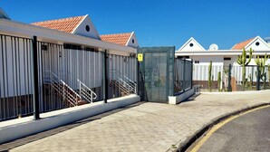 A building with a tiled roof, a gated entrance, and a paved walkway.