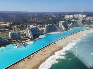 A coastal resort with multiple high-rise buildings, a long beachfront, and a central swimming area. - Greatest apartment ocean front (Algarrobo)