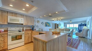 A modern kitchen with wooden cabinets, a large island, and a dining area with a view.