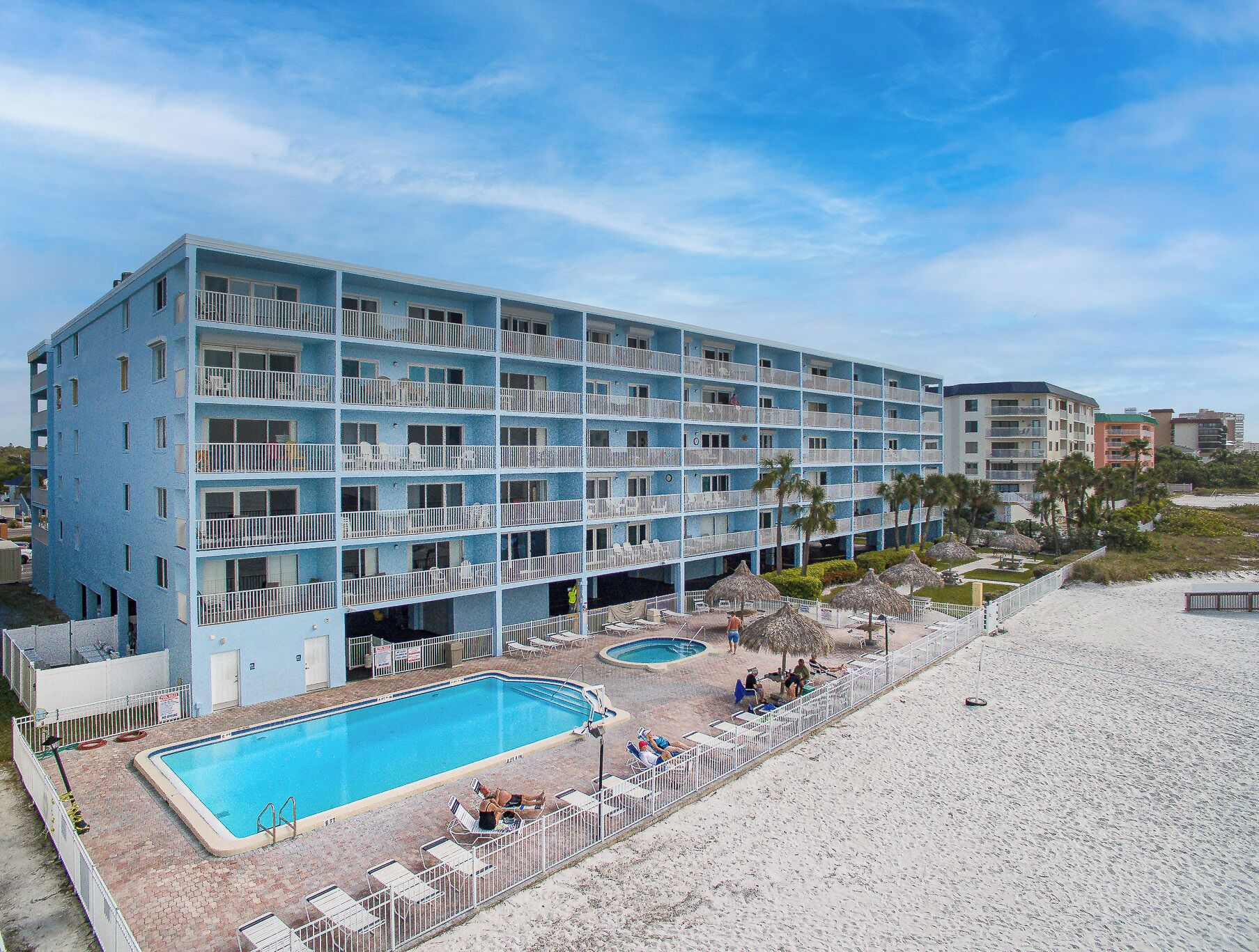 Ein mehrstöckiges Hotel mit Poolbereich, inklusive eines kleineren Pools und Liegestühlen.