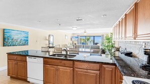 A spacious kitchen with wooden cabinets, a granite countertop, and a dishwasher. - Sand Dollar 204: 2  BR, 2  BA Condominium in Indian Shores, Sleeps 6 (Indian Shores)
