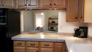A kitchen with wooden cabinets, a black refrigerator, a coffee maker, and a sink. - Gettysburg Getaway! Battlefields/Wineries/Ski! (Orrtanna)