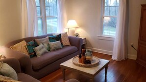 A cozy living room with a sofa, a small table with decorative items, and a lamp. - Gettysburg Getaway! Battlefields/Wineries/Ski! (Orrtanna)