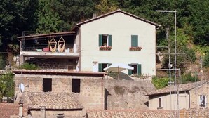 A two-story building with a balcony, surrounded by other buildings with terracotta roofs. - 2-storey vacation home with 2 large terraces and sensational views (Mazzano Romano)