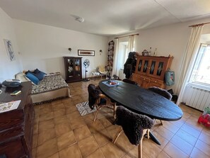 Ein Wohnzimmer mit einer Couch, einem Esstisch und einem Schrank.