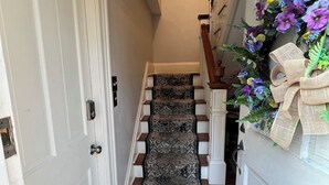 Una escalera con alfombra estampada y un arreglo floral decorativo.