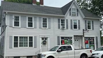 A two-story white building with a garage, a driveway, and a street.