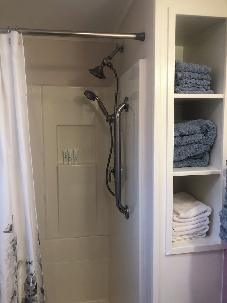 Une douche avec un pommeau de douche amovible et un porte-serviettes.
