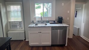 Una cocina moderna con lavavajillas integrado, una ventana con persianas y un radiador.