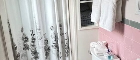 A bathroom with a toilet, sink, and a shelf with towels.