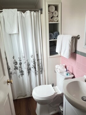 Baño con inodoro, lavamanos y repisa con toallas.