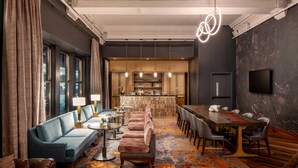 Un moderno vestíbulo de hotel con un sofá largo, una mesa de comedor y una zona de bar.