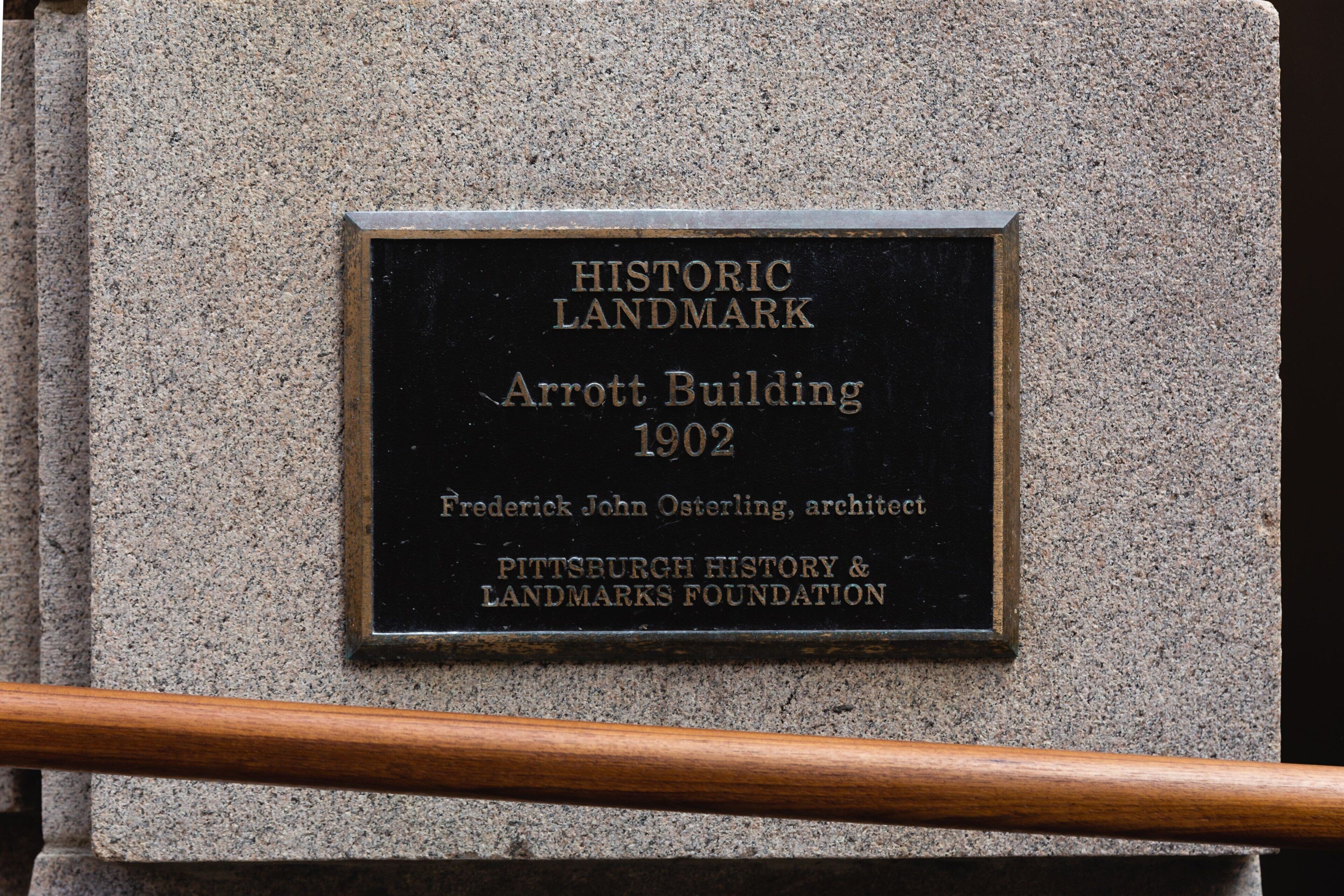 Une plaque commémorative fixée à un mur de pierre marque l’emplacement historique de l’immeuble Arrott, construit en 1902 et conçu par Frederick John Osterling.