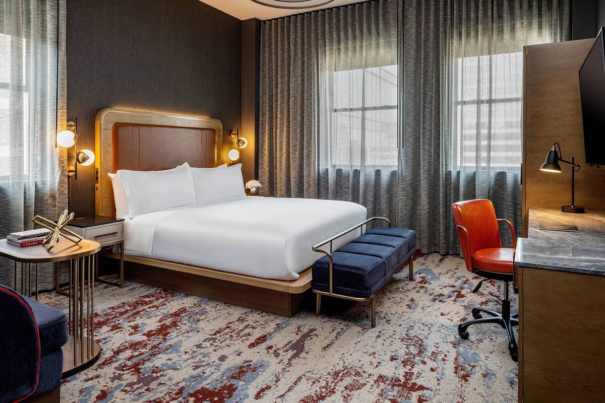 A hotel room with a large bed, bedside tables, a desk, and a chair.