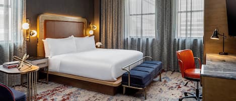 Una habitación de hotel con una cama grande, mesitas de noche, un escritorio y una silla.
