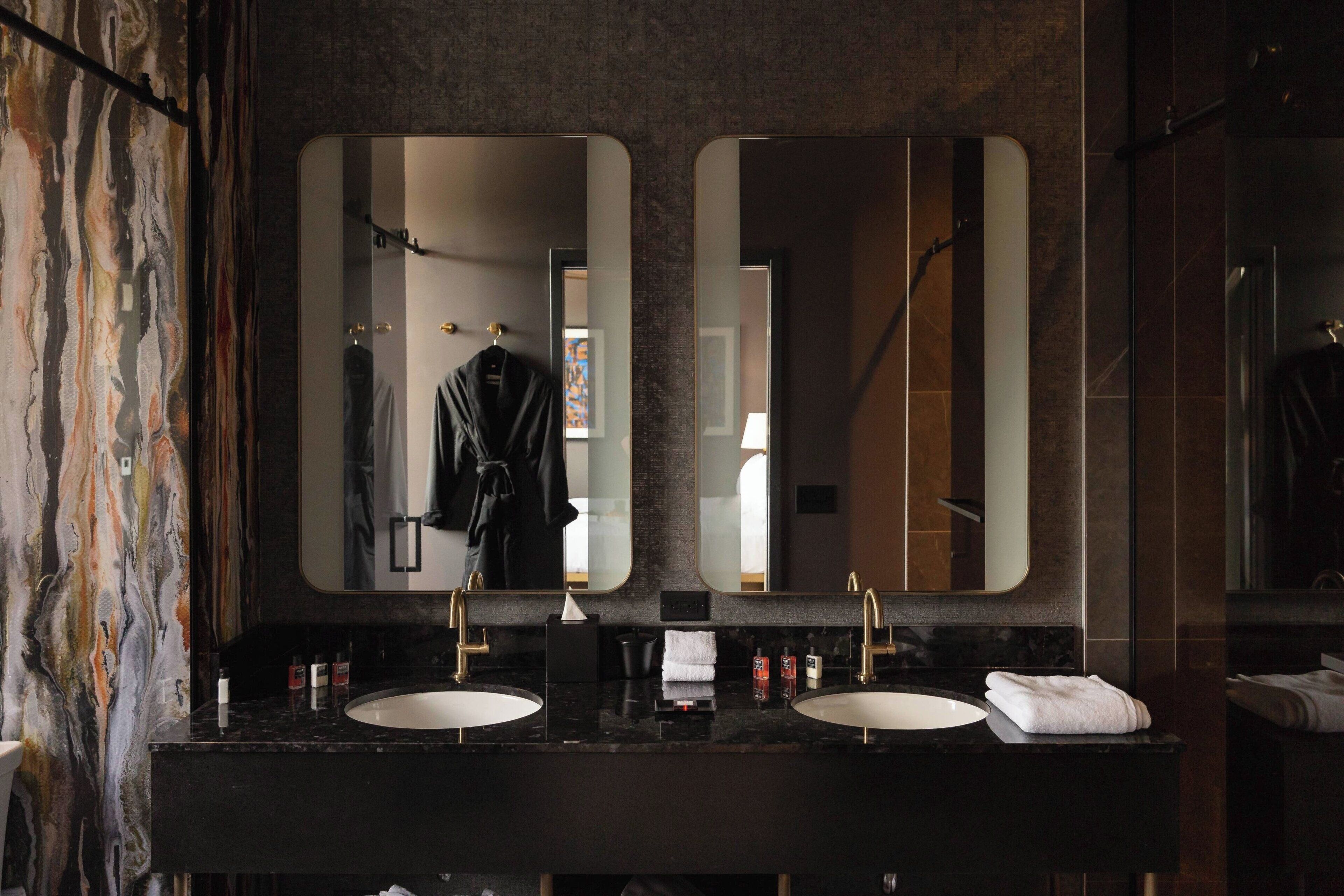A bathroom with two sinks, a large mirror, and a towel rack.